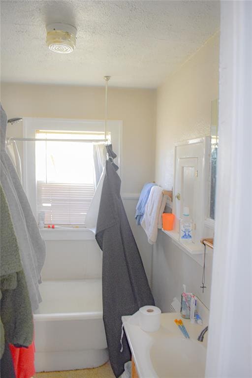 bathroom featuring a textured ceiling, vanity, and shower / bathtub combination with curtain