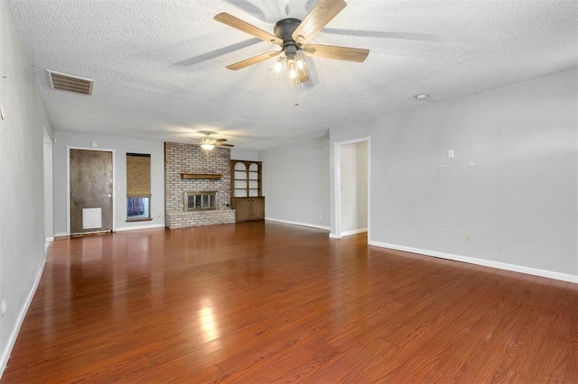 unfurnished living room with a fireplace, ceiling fan, dark hardwood / wood-style flooring, and a textured ceiling