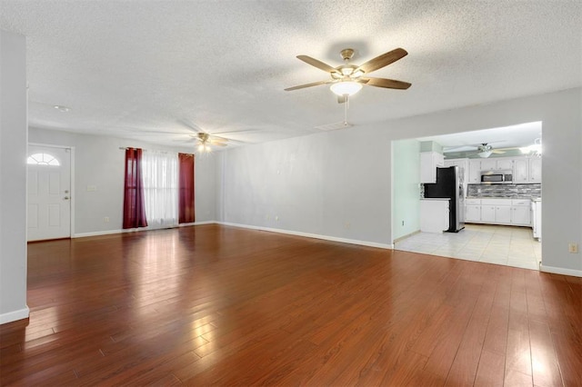 unfurnished living room with a textured ceiling and light hardwood / wood-style flooring