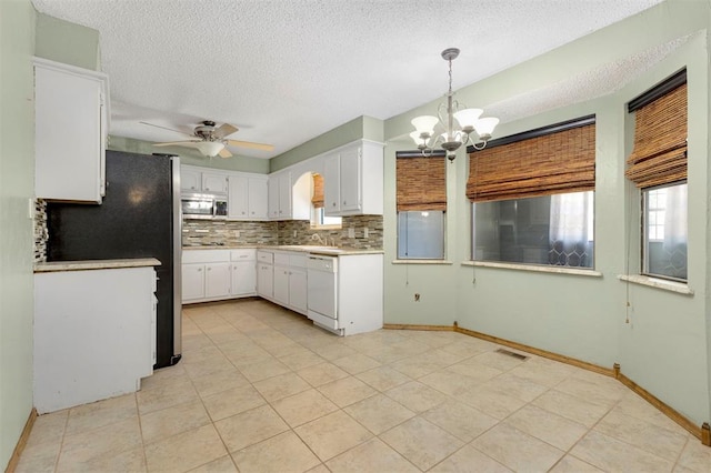 kitchen featuring pendant lighting, white dishwasher, ceiling fan with notable chandelier, a textured ceiling, and white cabinetry