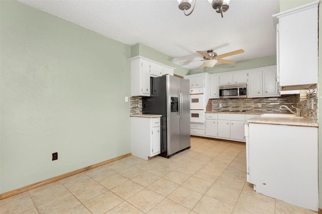 kitchen featuring decorative backsplash, appliances with stainless steel finishes, white cabinetry, and sink