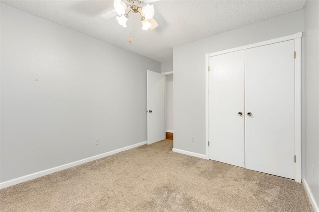 unfurnished bedroom featuring light carpet, a textured ceiling, a closet, and ceiling fan