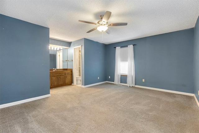 unfurnished bedroom with ensuite bath, ceiling fan, light carpet, and a textured ceiling