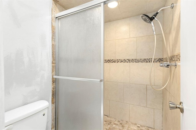 bathroom with a shower with door and toilet