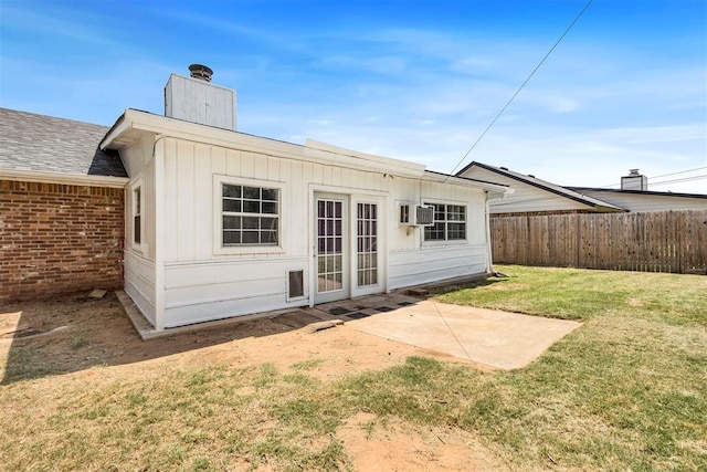 rear view of property with a wall mounted air conditioner, a patio area, and a lawn