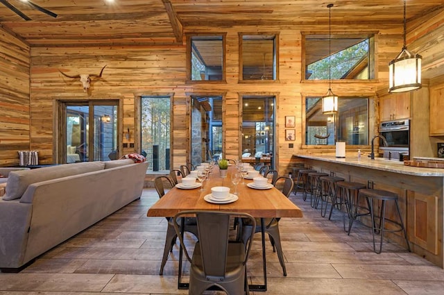 dining space featuring wood-type flooring, sink, and high vaulted ceiling