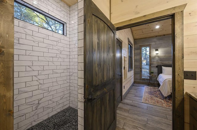 bathroom with wood walls, vanity, wood-type flooring, and vaulted ceiling