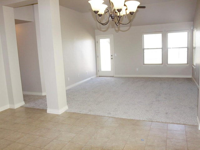 spare room with a chandelier and light carpet