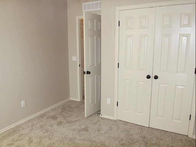 unfurnished bedroom with light colored carpet and a closet