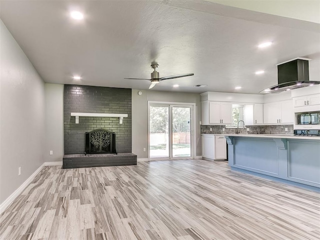 kitchen featuring a kitchen breakfast bar, black microwave, white cabinets, and light hardwood / wood-style floors