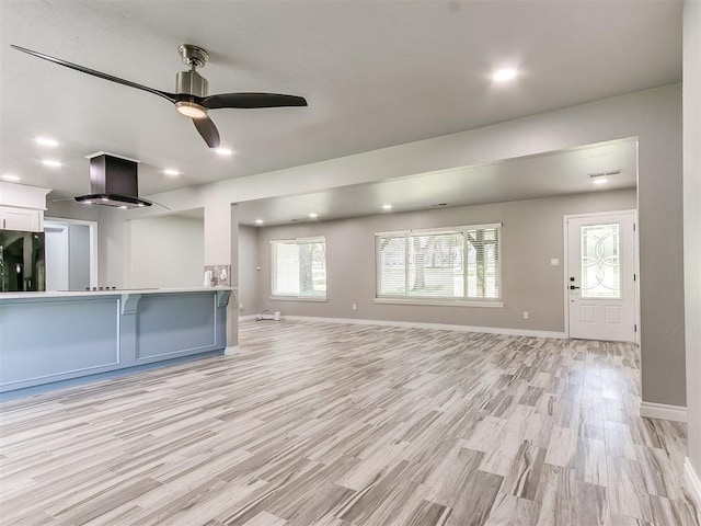 unfurnished living room featuring ceiling fan and light wood-type flooring