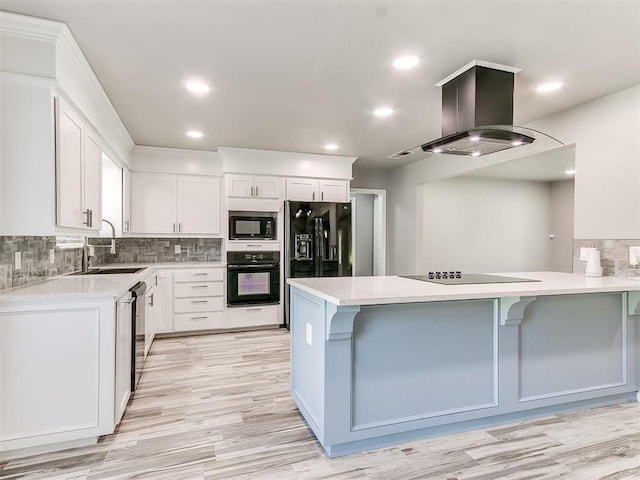 kitchen featuring white cabinets, black appliances, a kitchen bar, and sink