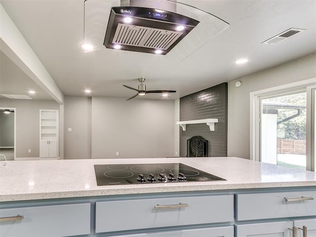 kitchen with backsplash, a brick fireplace, ceiling fan, light stone countertops, and black electric cooktop