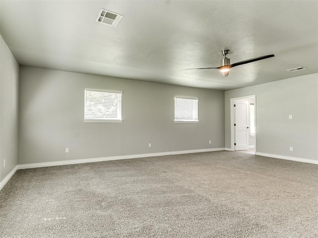 empty room featuring carpet flooring, ceiling fan, and a wealth of natural light