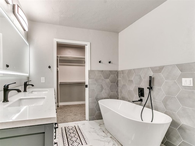 bathroom featuring a textured ceiling, a tub, vanity, and tile walls