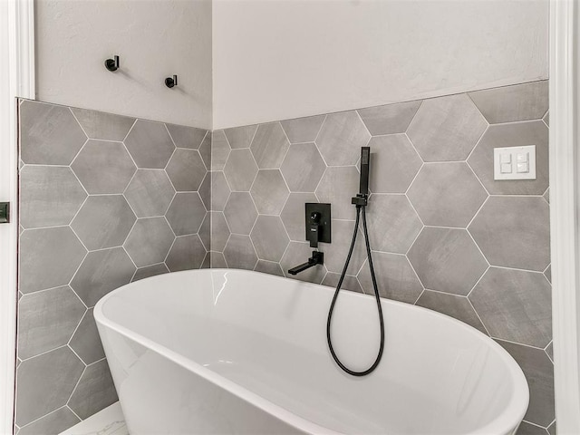 bathroom featuring sink, a bath, and tile walls