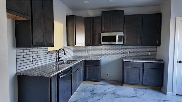 kitchen with decorative backsplash, appliances with stainless steel finishes, light stone countertops, dark brown cabinetry, and sink