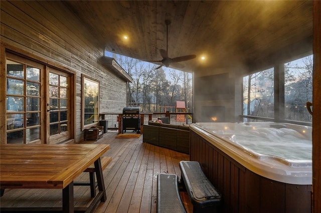 deck at dusk with ceiling fan, area for grilling, and a hot tub