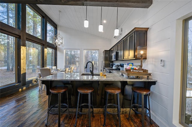 kitchen featuring dark wood-type flooring, sink, hanging light fixtures, light stone countertops, and stainless steel appliances