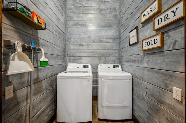 clothes washing area with independent washer and dryer and wood walls