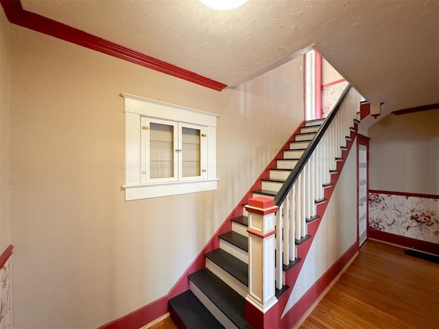 staircase featuring hardwood / wood-style floors and ornamental molding