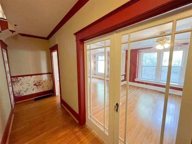 corridor with a wealth of natural light, hardwood / wood-style floors, and crown molding