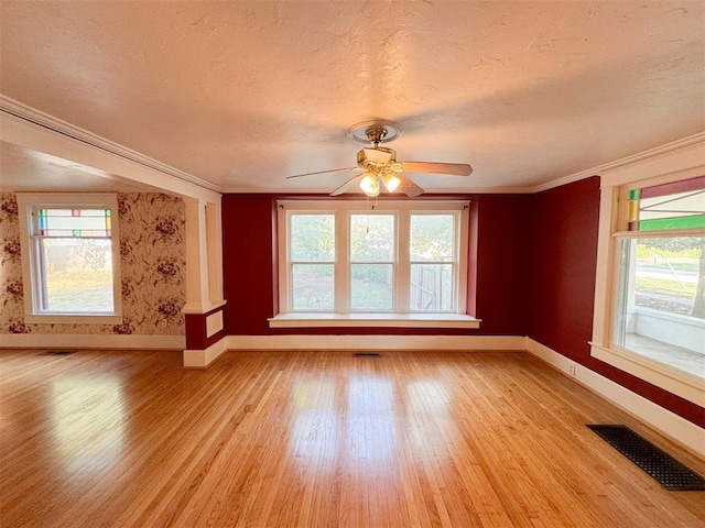 unfurnished living room featuring a textured ceiling, light hardwood / wood-style floors, ceiling fan, and crown molding