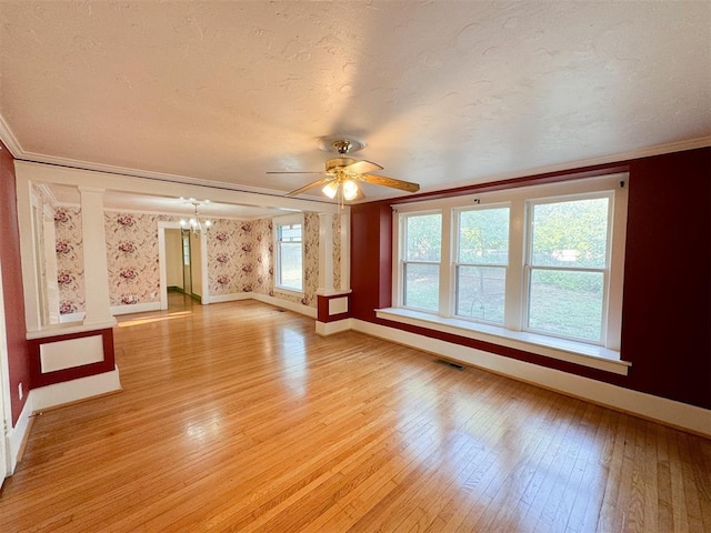 empty room with ceiling fan with notable chandelier, a textured ceiling, light wood-type flooring, and crown molding