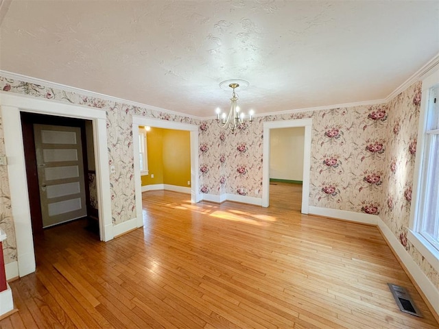 unfurnished room with an inviting chandelier, ornamental molding, and hardwood / wood-style flooring