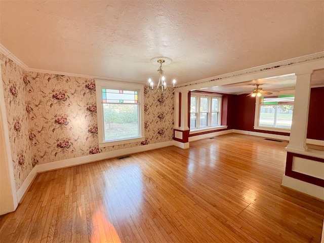 unfurnished room with crown molding, a healthy amount of sunlight, ceiling fan with notable chandelier, and hardwood / wood-style flooring