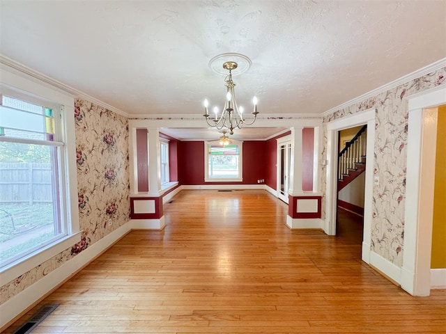 interior space featuring light wood-type flooring, ornamental molding, and an inviting chandelier