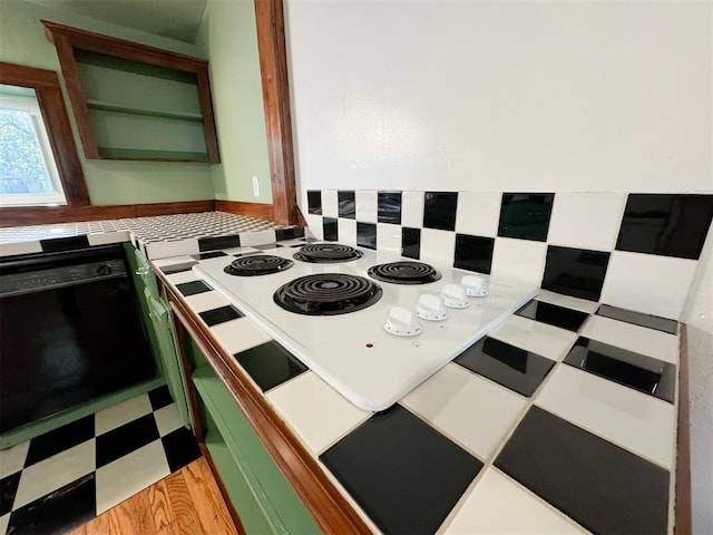 kitchen featuring black oven, green cabinets, and light hardwood / wood-style floors