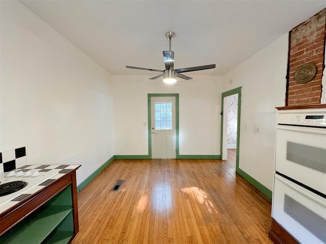 kitchen featuring ceiling fan, light hardwood / wood-style floors, and white double oven