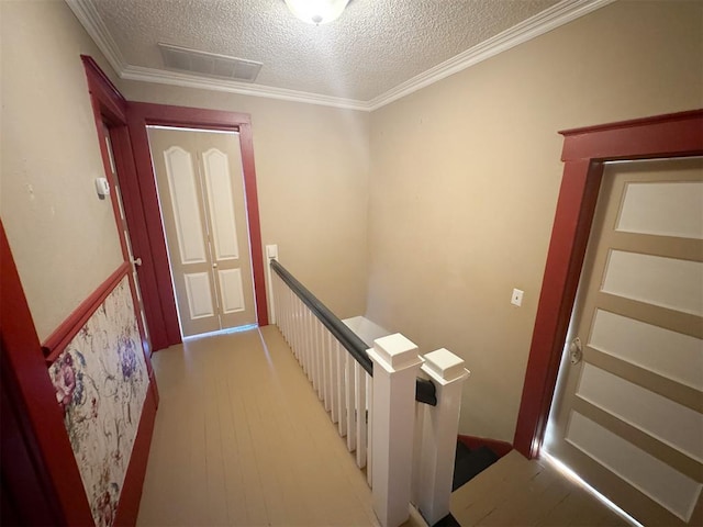 hall featuring hardwood / wood-style floors, a textured ceiling, and ornamental molding