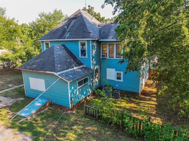 rear view of property featuring a yard and central AC unit