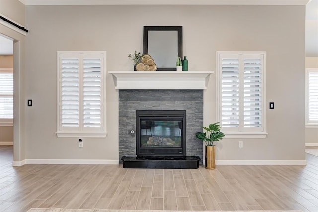 unfurnished living room with light hardwood / wood-style flooring and a stone fireplace