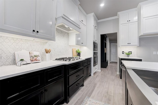 kitchen with white cabinets, appliances with stainless steel finishes, light wood-type flooring, and ornamental molding