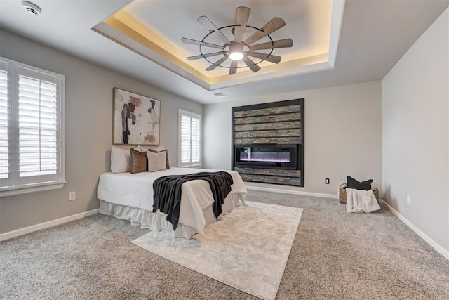 bedroom with carpet flooring, a raised ceiling, and ceiling fan