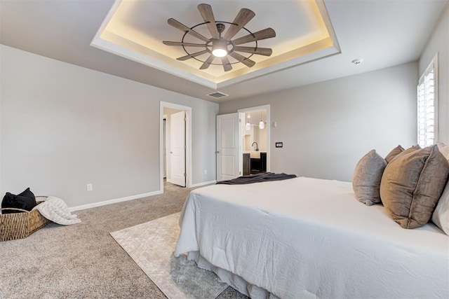 carpeted bedroom with a tray ceiling and ceiling fan