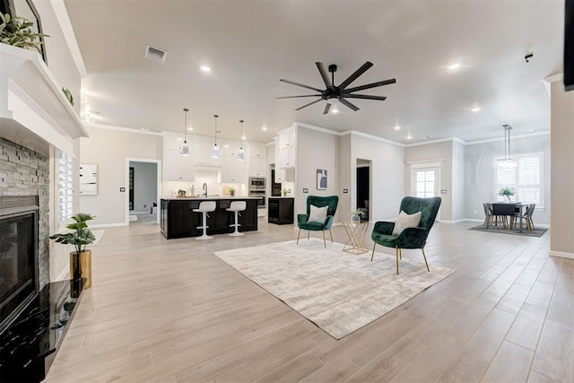 living room featuring crown molding, light wood-type flooring, and a fireplace