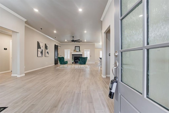 unfurnished living room featuring ceiling fan, crown molding, and light hardwood / wood-style floors