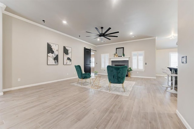 interior space featuring a barn door, crown molding, ceiling fan, and light hardwood / wood-style floors