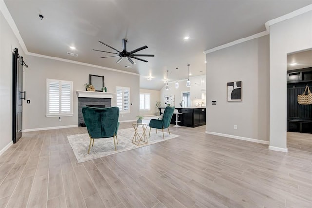 unfurnished living room featuring a barn door, light hardwood / wood-style floors, and ornamental molding