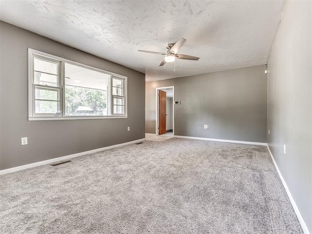 carpeted spare room with a textured ceiling and ceiling fan