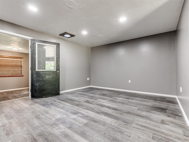 empty room with a textured ceiling and light hardwood / wood-style flooring