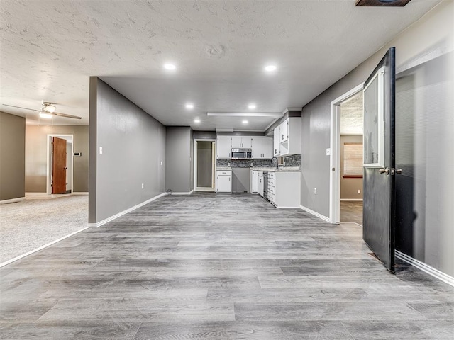 kitchen with white cabinetry, ceiling fan, and light hardwood / wood-style floors