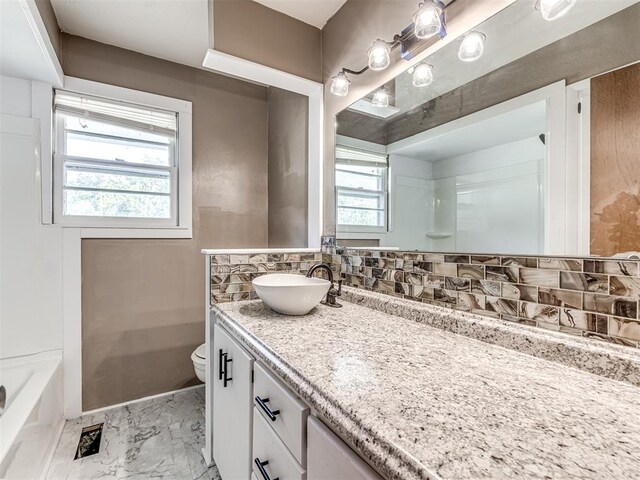 bathroom featuring vanity, a healthy amount of sunlight, toilet, and tasteful backsplash