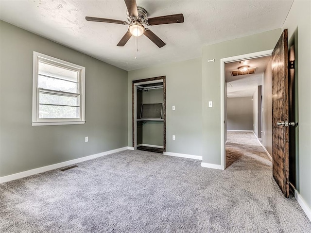 unfurnished bedroom featuring ceiling fan, light colored carpet, and a textured ceiling