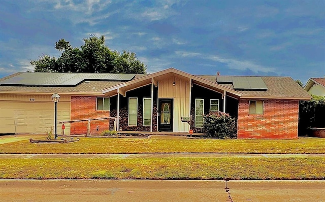 view of front of house featuring solar panels, a porch, a garage, and a front yard