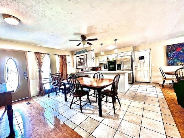 dining area with ceiling fan, light tile patterned floors, and a textured ceiling